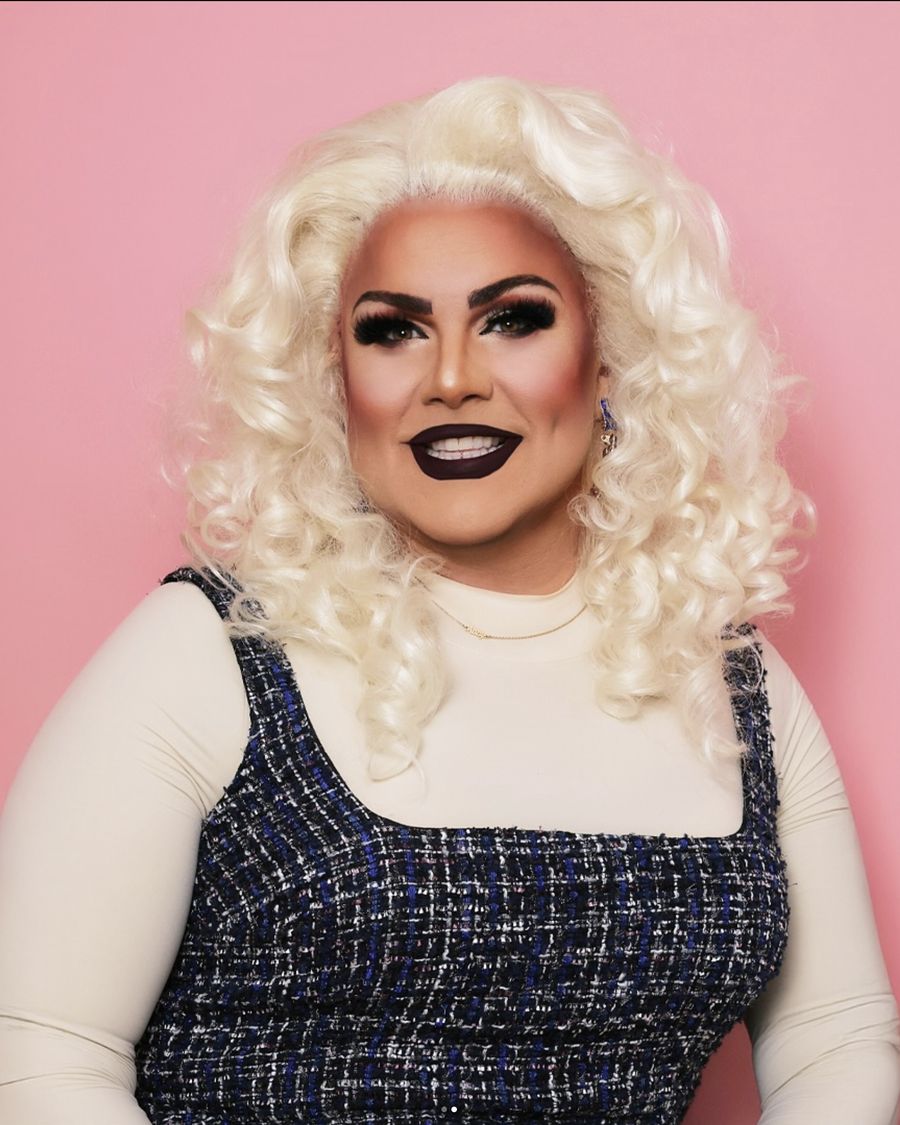 Abby Cummings smiling warmly in a tweed dress with platinum curls