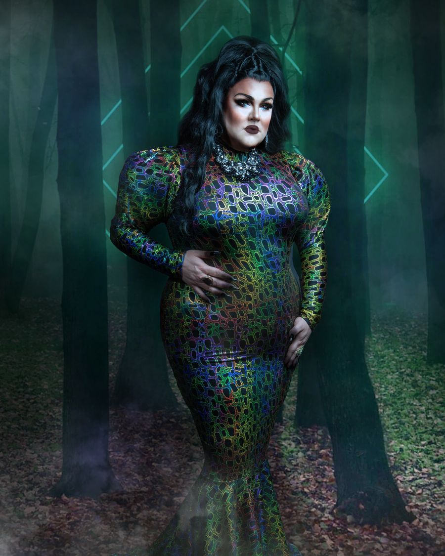 Abby Cummings in a jewel-toned gown standing in a misty New England forest