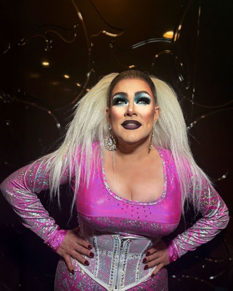 Abby in a pink corseted costume under warm lights