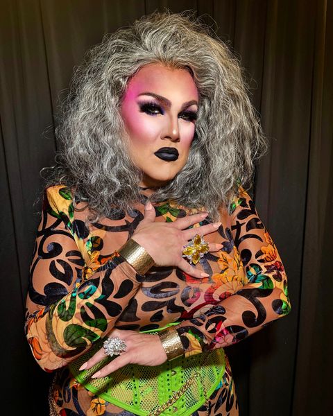 Abby with silver hair in a printed bodysuit and gold cuffs
